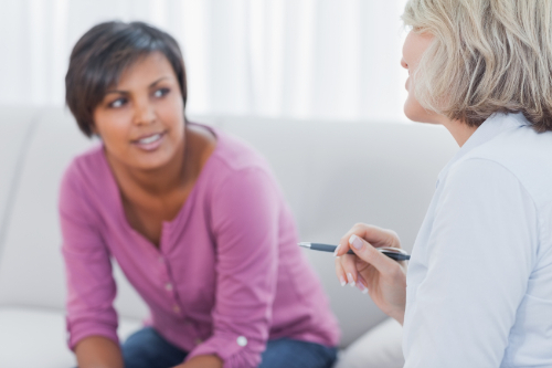 Therapist advising her smiling patient on couch in office